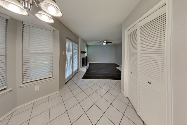 interior space featuring light tile patterned flooring, ceiling fan, and baseboards