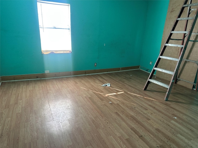 spare room featuring baseboards and wood finished floors