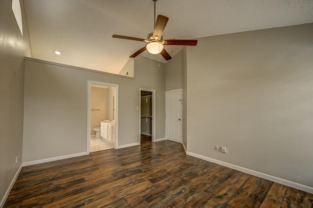 unfurnished bedroom with baseboards, connected bathroom, dark wood-type flooring, a walk in closet, and a closet