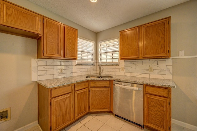 kitchen featuring dishwasher, decorative backsplash, a sink, and light stone countertops