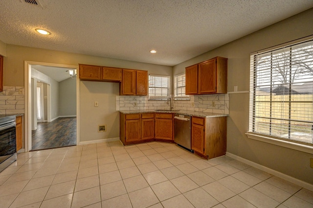 kitchen with decorative backsplash, brown cabinets, stainless steel appliances, a sink, and light tile patterned flooring