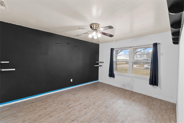 empty room featuring ceiling fan, light wood finished floors, visible vents, and baseboards