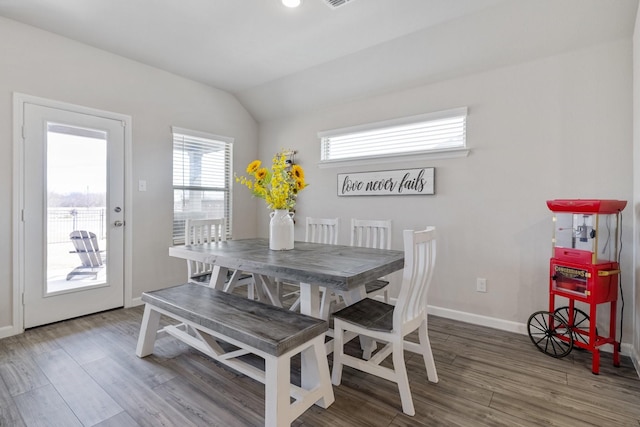 dining space with vaulted ceiling, wood finished floors, and baseboards