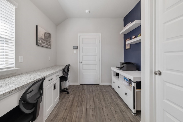 office space featuring lofted ceiling, baseboards, dark wood-style flooring, and built in study area