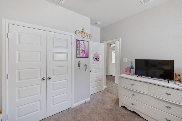 bedroom with baseboards, a closet, and light colored carpet