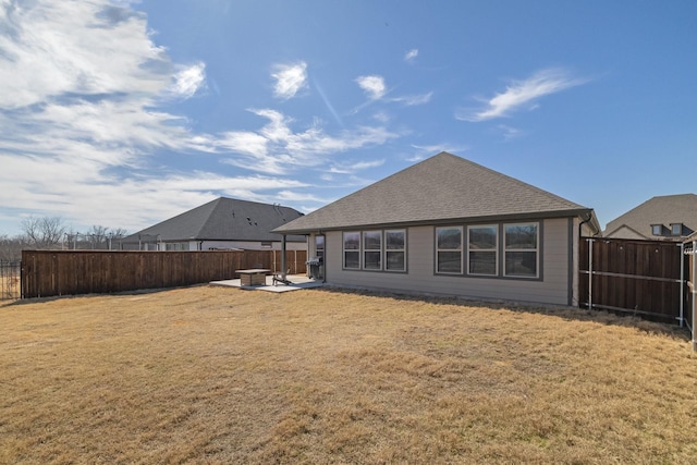 back of property with a yard, a fenced backyard, a patio, and roof with shingles