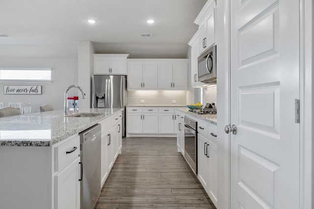 kitchen with a kitchen island with sink, white cabinetry, and stainless steel appliances