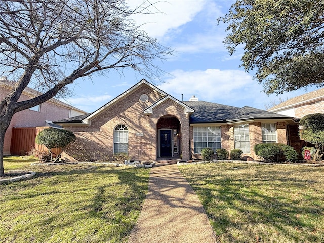 ranch-style home featuring a shingled roof, fence, a front lawn, and brick siding