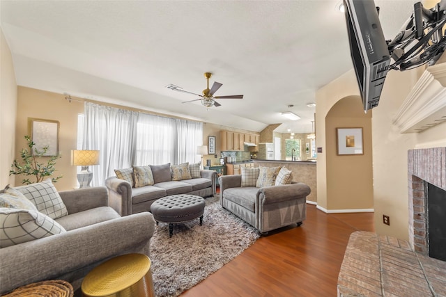 living area with ceiling fan, wood finished floors, baseboards, and a fireplace