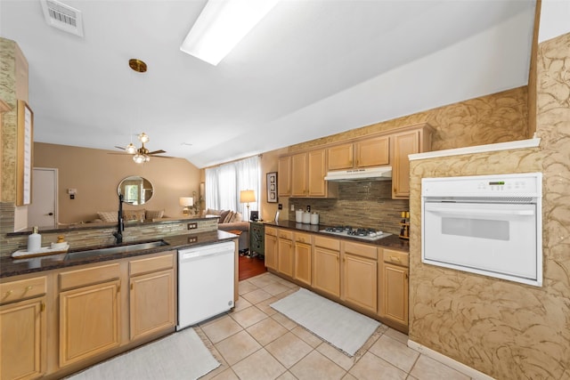 kitchen with white appliances, under cabinet range hood, light tile patterned flooring, tasteful backsplash, and vaulted ceiling