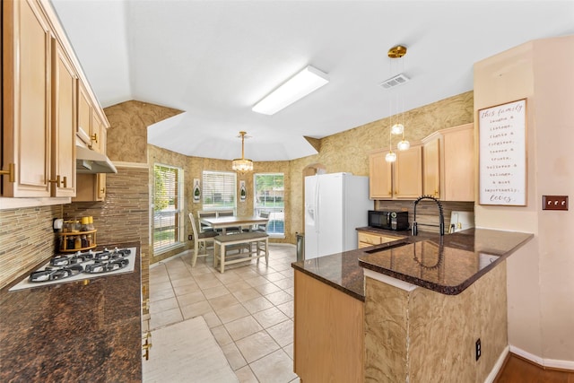 kitchen featuring white appliances, tasteful backsplash, light brown cabinetry, pendant lighting, and lofted ceiling