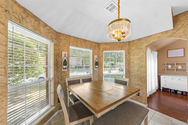 tiled dining room featuring a chandelier and arched walkways
