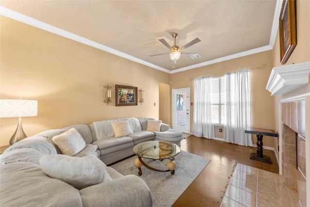living area with ceiling fan, crown molding, a fireplace, and baseboards