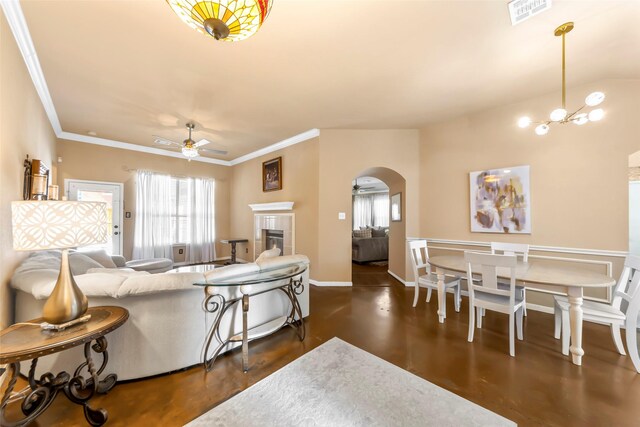 living area featuring a ceiling fan, arched walkways, ornamental molding, a tile fireplace, and dark wood-style floors