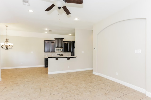 kitchen featuring visible vents, stainless steel microwave, open floor plan, a breakfast bar area, and backsplash