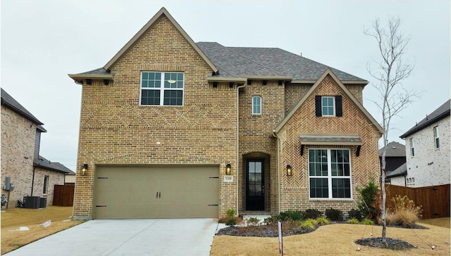 view of front facade with brick siding, an attached garage, central AC unit, fence, and driveway