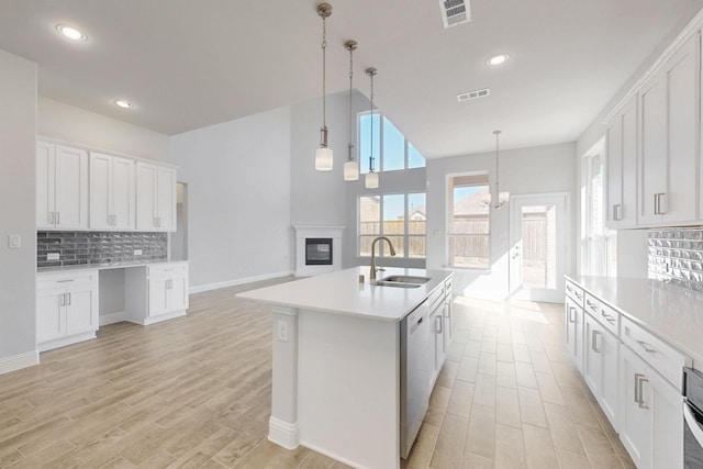 kitchen with visible vents, white cabinetry, light countertops, and a sink