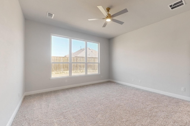 carpeted spare room with baseboards, visible vents, and a ceiling fan