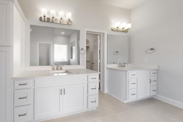 full bathroom with baseboards, two vanities, a sink, and tile patterned floors