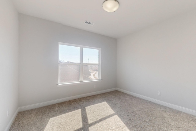 empty room featuring carpet, visible vents, and baseboards