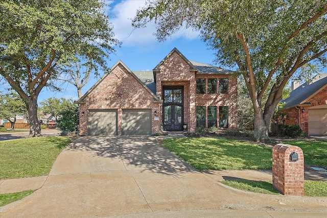 traditional-style house featuring a front yard, driveway, an attached garage, french doors, and brick siding