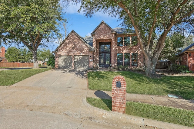 traditional home featuring brick siding, concrete driveway, an attached garage, a front yard, and fence