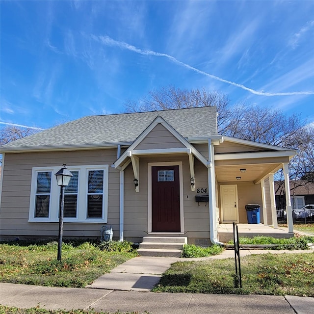 bungalow featuring entry steps, an attached carport, and a shingled roof