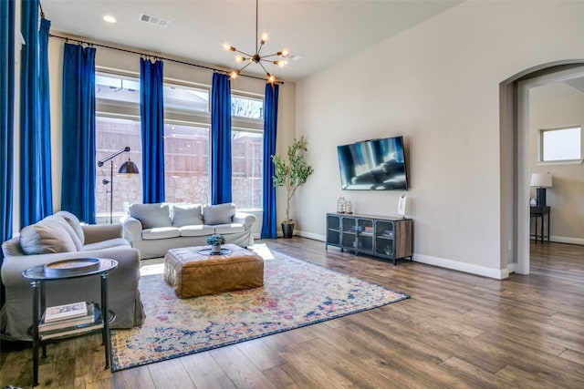 living room featuring arched walkways, a notable chandelier, visible vents, dark wood-type flooring, and baseboards