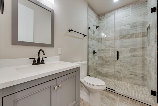 full bath featuring toilet, a shower stall, and vanity