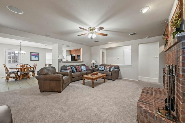 living room featuring light carpet, a fireplace, visible vents, and ceiling fan with notable chandelier