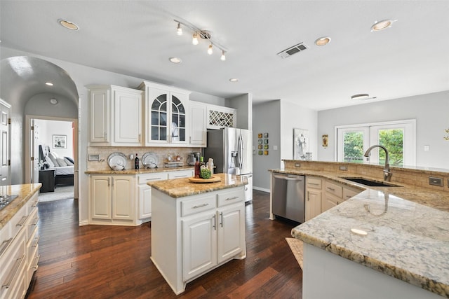 2781 Timber Crest Ln, Highland Village, TX 75077 - kitchen with stainless steel appliances, a sink, a center island, arched walkways, and backsplash