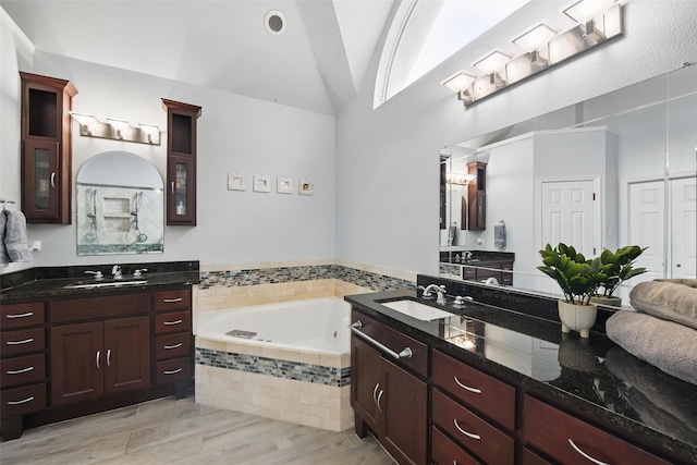 2781 Timber Crest Ln, Highland Village, TX 75077 - bathroom featuring a garden tub, two vanities, vaulted ceiling, and wood finished floors