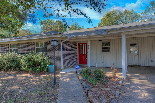 4606 Tibbs St, Shreveport, LA 71105 - view of exterior entry featuring brick siding, board and batten siding, and a carport