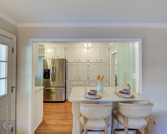 4606 Tibbs St, Shreveport, LA 71105 - kitchen with stainless steel fridge, light wood-style flooring, crown molding, a kitchen bar, and white cabinetry