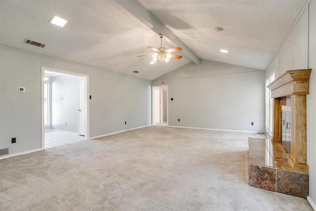 unfurnished living room featuring vaulted ceiling with beams, a fireplace, light colored carpet, visible vents, and a textured ceiling