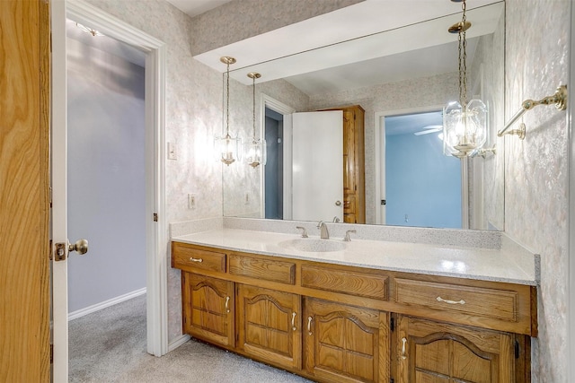 bathroom featuring a chandelier, wallpapered walls, vanity, and baseboards