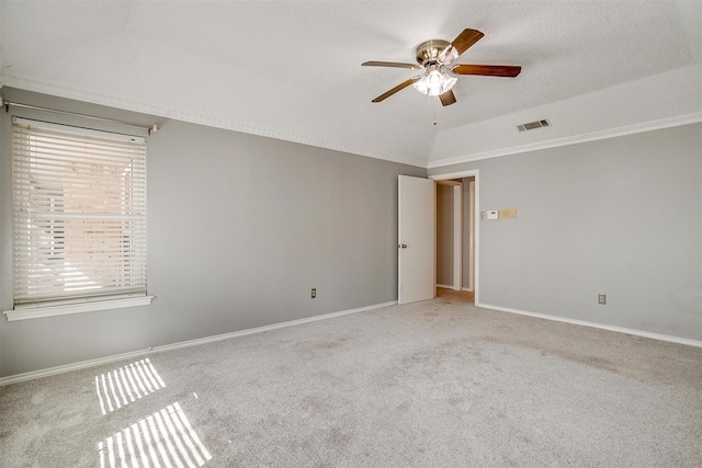 empty room with light carpet, a ceiling fan, visible vents, vaulted ceiling, and baseboards