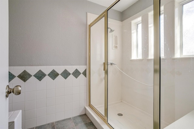 full bath featuring a healthy amount of sunlight, a stall shower, tile walls, and a textured wall