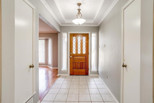 foyer featuring a textured ceiling, a raised ceiling, and crown molding