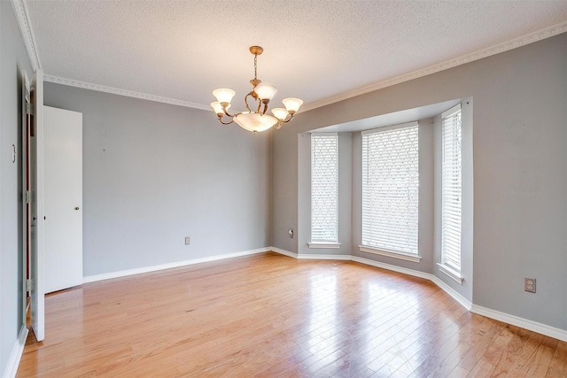 empty room featuring crown molding, light wood-style flooring, a textured ceiling, and an inviting chandelier