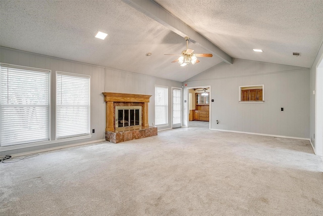 unfurnished living room featuring lofted ceiling with beams, a textured ceiling, light carpet, a ceiling fan, and a glass covered fireplace