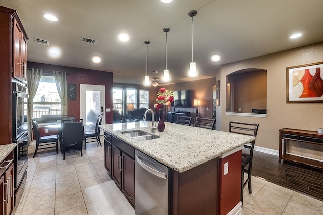 kitchen featuring pendant lighting, stainless steel appliances, a sink, an island with sink, and a kitchen breakfast bar