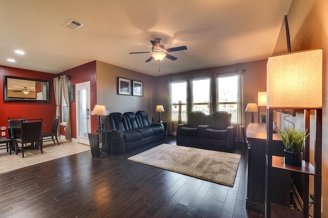 living room featuring a ceiling fan, visible vents, and wood finished floors