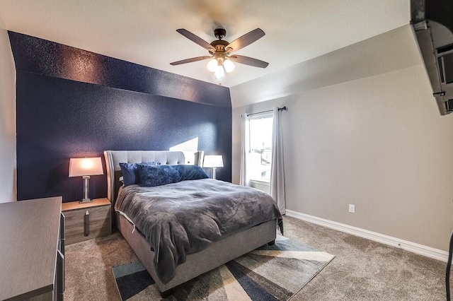 carpeted bedroom featuring an accent wall, vaulted ceiling, ceiling fan, and baseboards