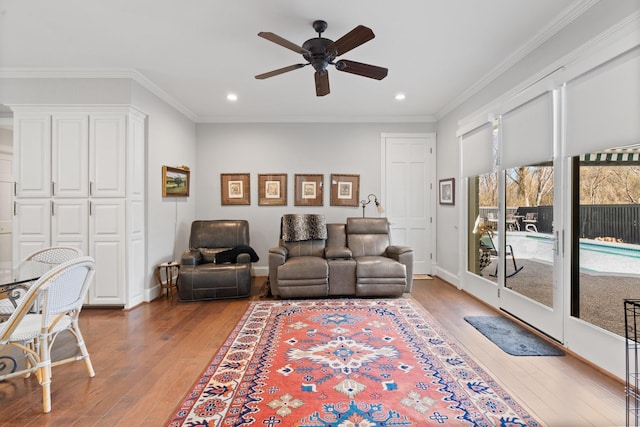 living area featuring baseboards, ceiling fan, ornamental molding, and wood finished floors