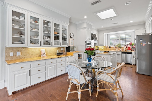 kitchen with visible vents, appliances with stainless steel finishes, glass insert cabinets, and white cabinets