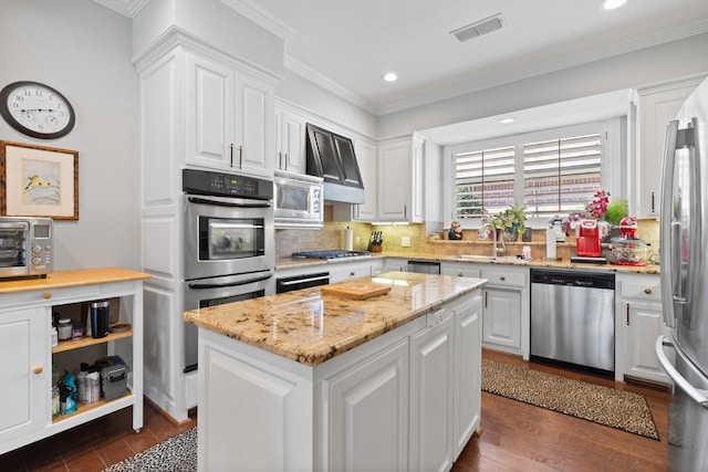 kitchen featuring white cabinets, visible vents, stainless steel appliances, and a center island