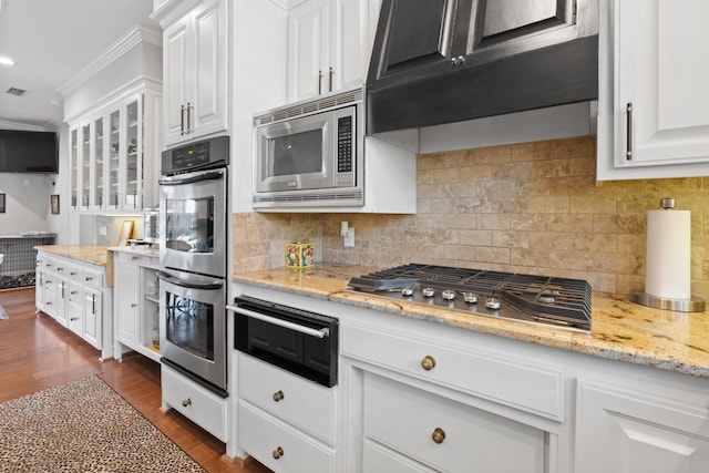 kitchen with a warming drawer, stainless steel appliances, glass insert cabinets, white cabinets, and under cabinet range hood