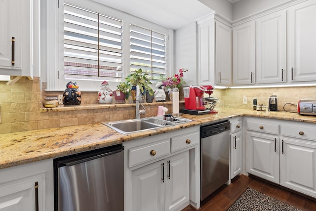 kitchen featuring decorative backsplash, white cabinets, dishwasher, and a sink