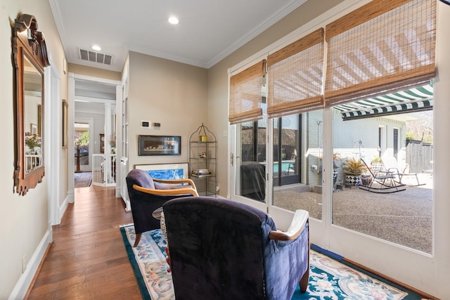 living area with dark wood-style floors, recessed lighting, visible vents, ornamental molding, and baseboards